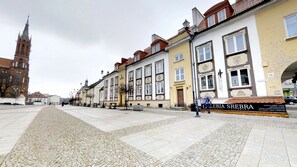 A street with historic buildings, a prominent church tower, and a sign for 'Galeria Srebra'.