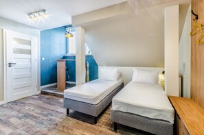A room with two single beds, a wooden table, a small desk, and a chair.
