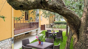 Un patio exterior con mobiliario de mimbre y una mesa con un centro de flores.
