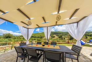 Un espacio al aire libre con mesa, sillas y vistas al campo.