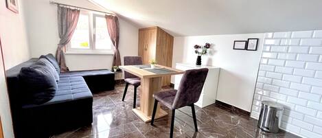 A compact living space with a sofa, a dining table, and a kitchen area.