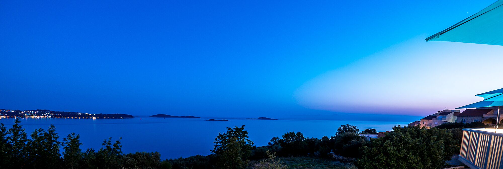 A coastal view with a clear sky, a calm sea, and a distant shoreline with buildings.