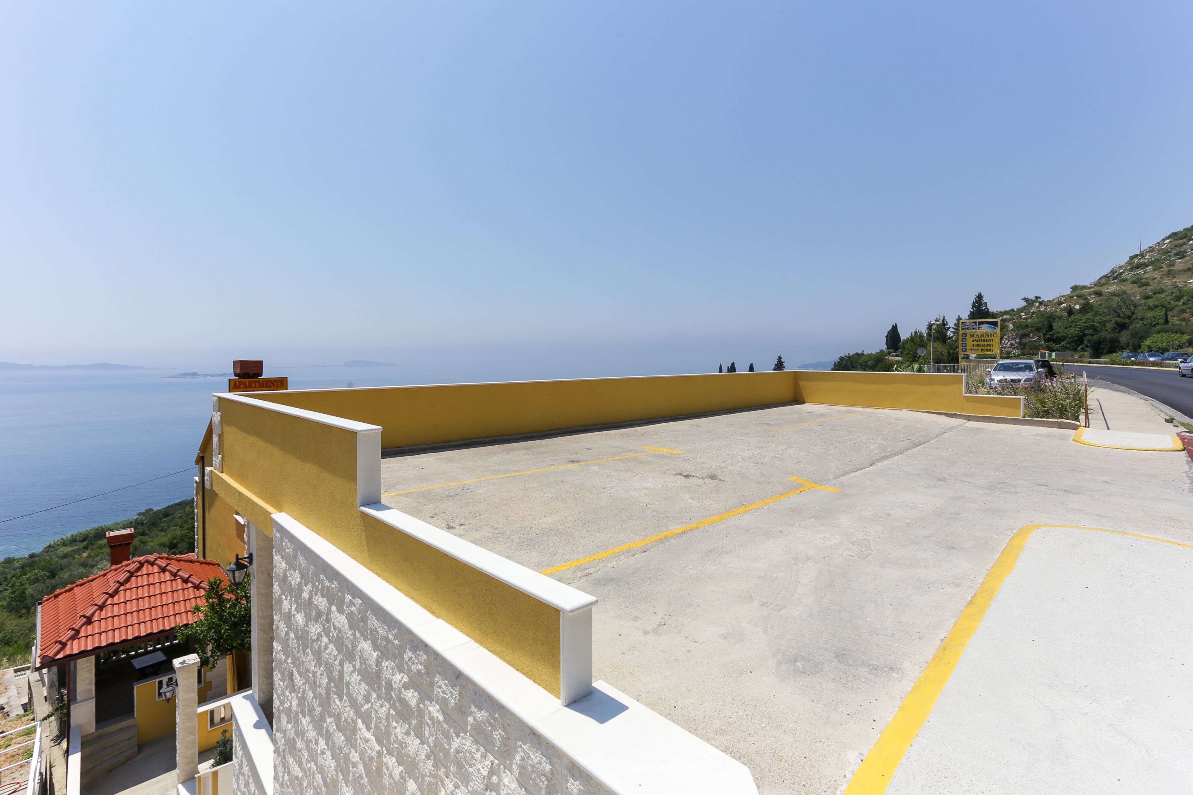 Ein Parkplatz mit einer gelben Wand und Blick auf das Meer.