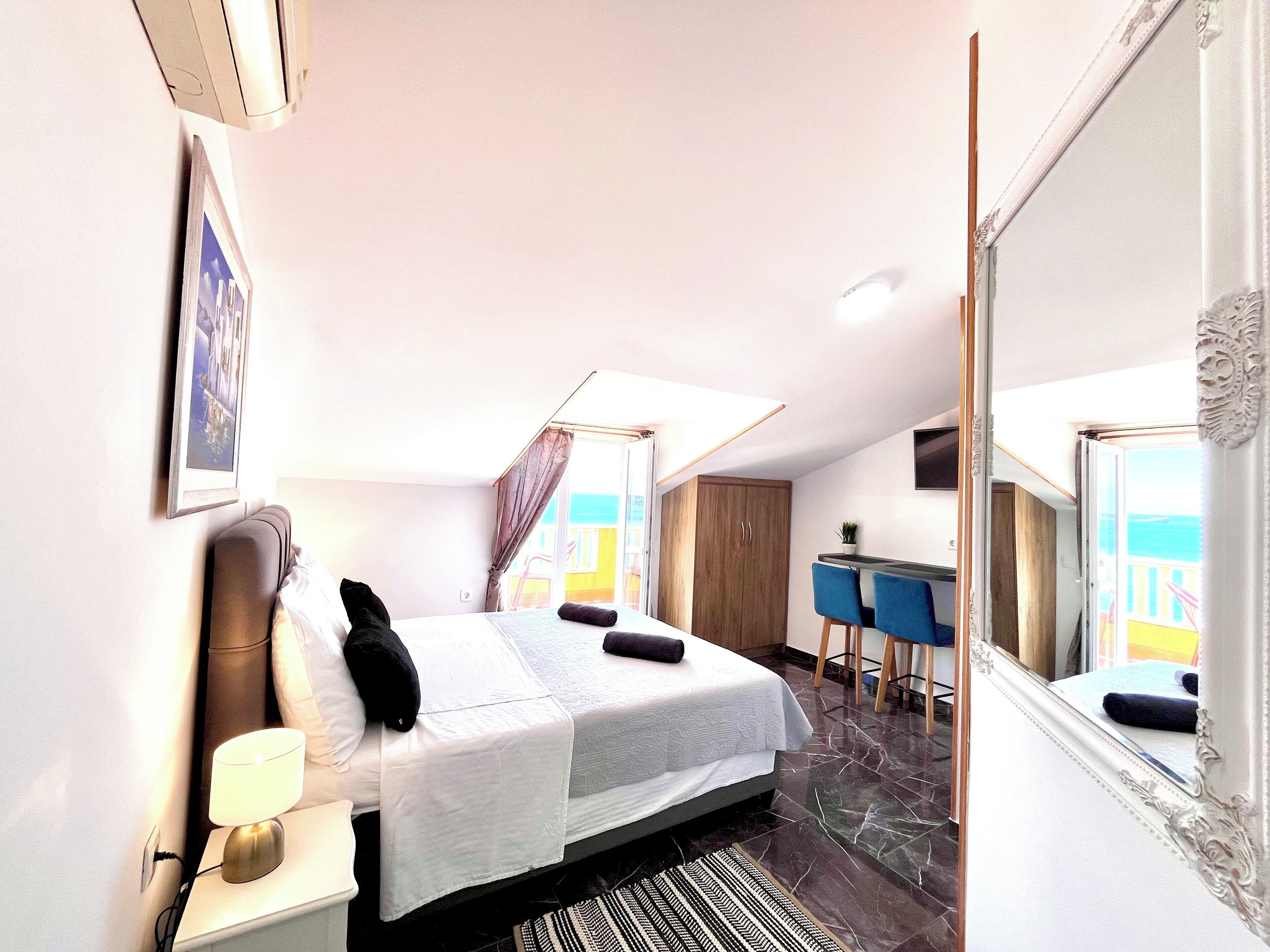 Una habitación de hotel con una cama, un escritorio, una silla, un espejo y una ventana.
