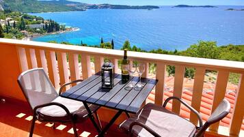 A balcony with a table, two chairs, a bottle of wine, and two glasses.