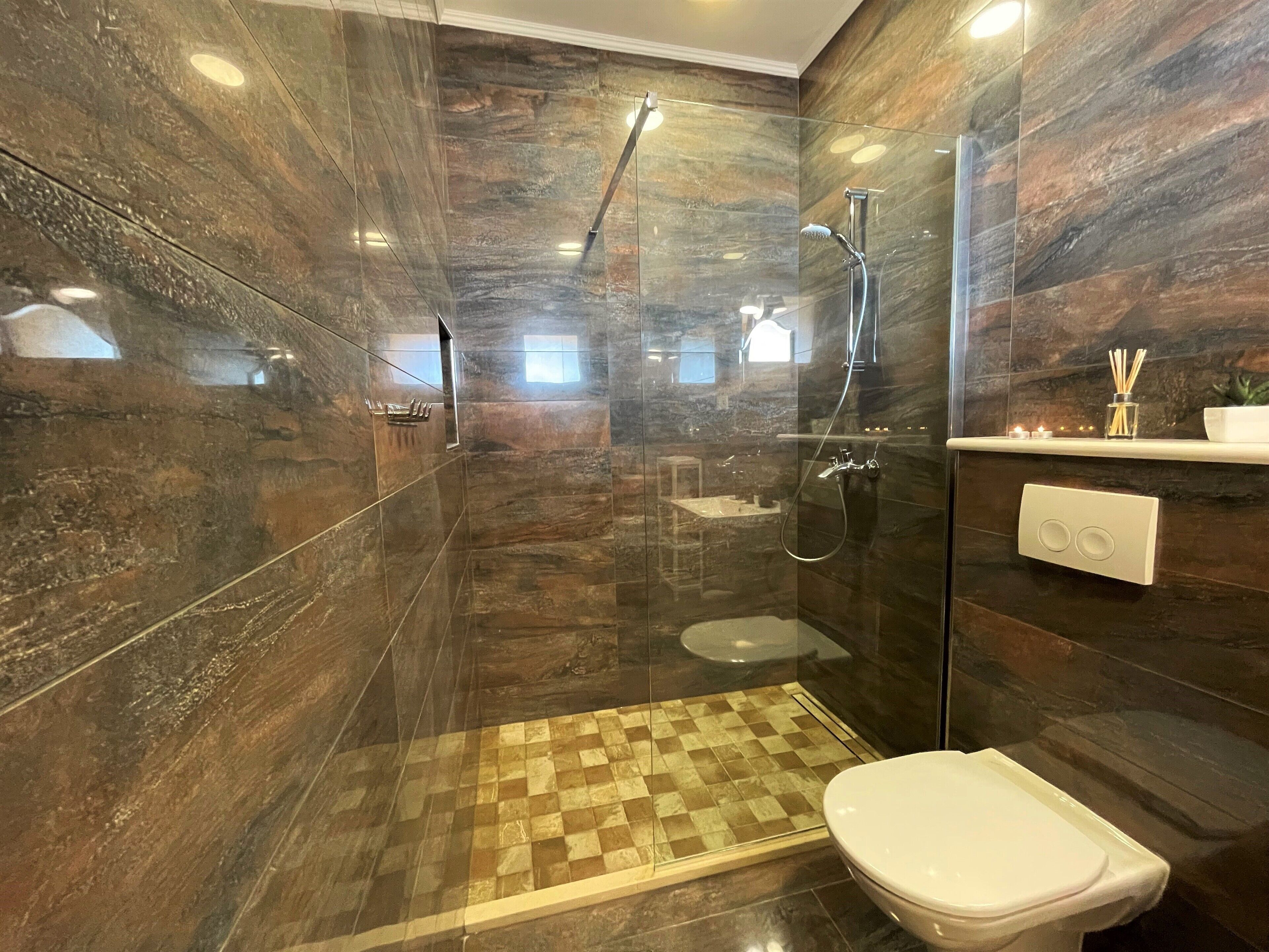 Un baño moderno con cabina de ducha de vidrio, suelo a cuadros y un inodoro.