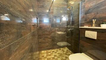 Un baño moderno con cabina de ducha de vidrio, suelo a cuadros y un inodoro.
