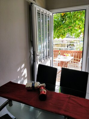 Un coin repas avec une table en verre, deux chaises et un chemin de table rouge.