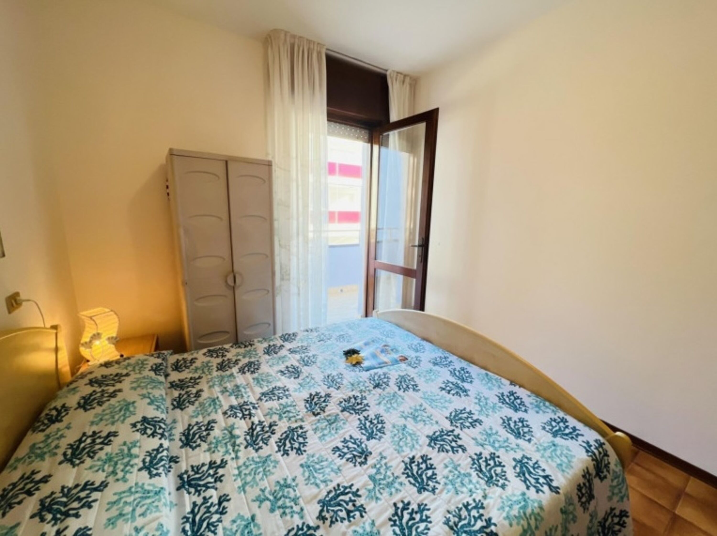 Une chambre à coucher avec un lit, une armoire et une fenêtre avec des rideaux.