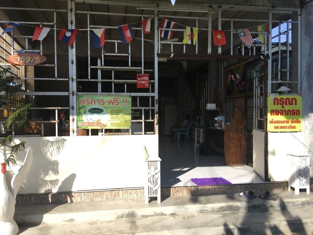 A building entrance with multiple flags, a sign indicating a 5-star rating, and a sign with Thai text.
