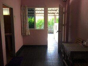 A narrow hallway with a window, a door, and a small table with a checkered tablecloth. - Mee Rak Resort (Bang Lamung)