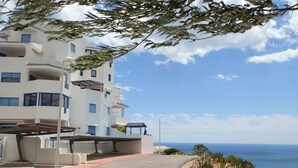 A coastal building with multiple balconies, a covered parking area, and a view of the sea. - SPAIN, PENISCOLA, apartment for rent in beautiful residence (Peniscola)