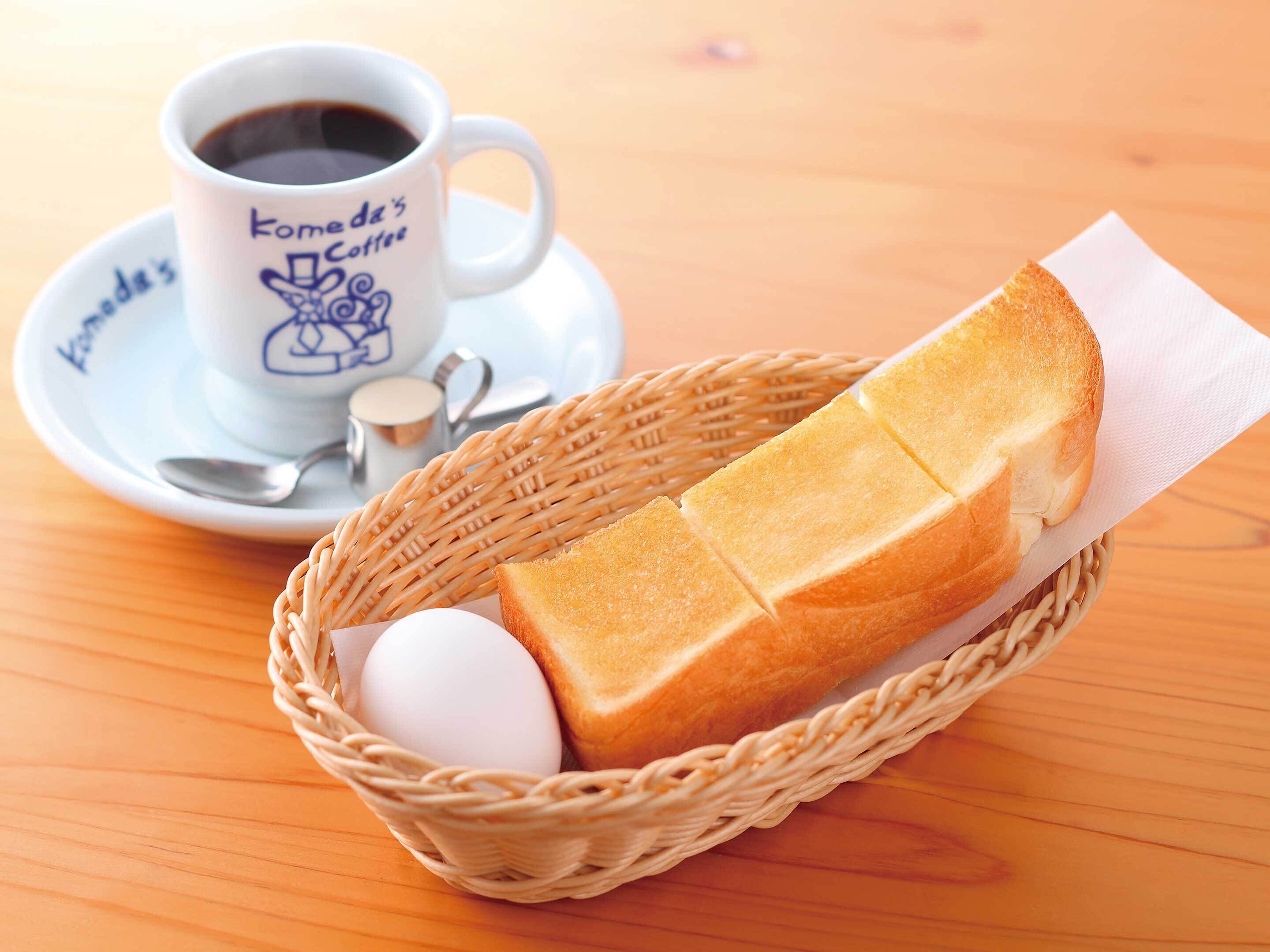 A wicker basket containing a baguette, an egg, and a napkin on a wooden table.