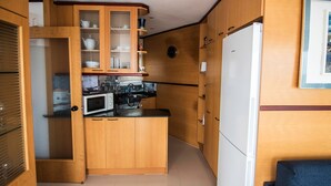 Une cuisine de taille réduite, dotée de meubles en bois, d’un four à micro-ondes et d’un réfrigérateur.