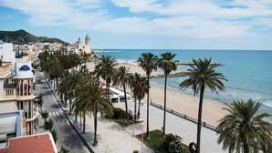 Un paysage urbain côtier avec une plage, des palmiers et un clocher d’église imposant.