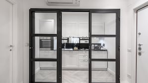Une cuisine moderne avec des meubles blancs, un plan de travail noir et un sol à motifs en chevrons.