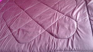 Uma cama com uma parede rosa ao fundo.