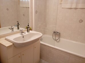 Un baño con lavamanos, espejo y bañera.
