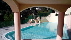 A swimming pool with a tiled deck, a covered area with columns, and a staircase leading to a higher level. - monaco holiday house blue coast montecarlo (Beausoleil)
