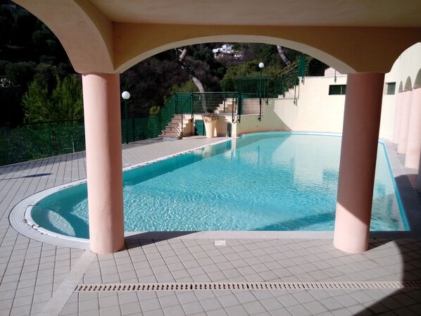 A swimming pool with a tiled deck, a covered area with columns, and a staircase leading to a higher level. - monaco holiday house blue coast montecarlo (Beausoleil)