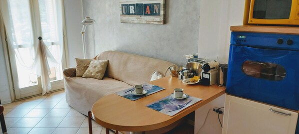 A cozy living room with a sofa, a small table with a cup and saucer, and a blue oven.