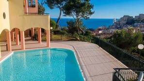 A swimming pool with a view of the sea and cityscape.