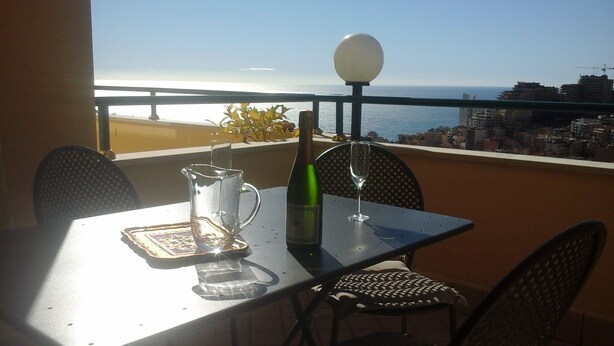 A balcony with a table, chairs, a bottle, a wine glass, and a pitcher. - monaco holiday house blue coast montecarlo (Beausoleil)