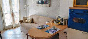 A cozy living area with a sofa, a table with a cup and saucer, and a blue appliance.