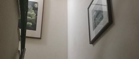 A staircase with a handrail, two lit candles on a stand, and framed pictures on the walls.