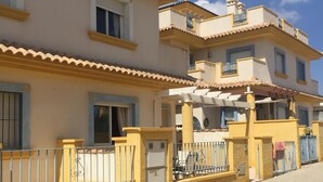 A multi-story building with balconies, a paved walkway, and a clear sky. - Stylish Villa, community pool typical Spanish village in La Tercia, Murcia  (Murcia)