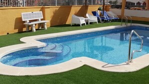 A swimming pool with a built-in jacuzzi, surrounded by artificial grass and white lounge chairs. - Stylish Villa, community pool typical Spanish village in La Tercia, Murcia  (Murcia)