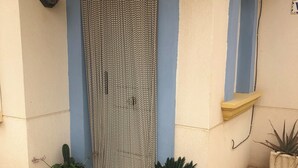 A building entrance with a blue door, a decorative screen, and potted plants. - Stylish Villa, community pool typical Spanish village in La Tercia, Murcia  (Murcia)