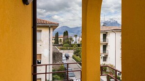A balcony with a view of a street, buildings, and mountains.