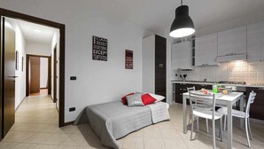 A compact living space with a kitchenette, a dining area, and a small bed.