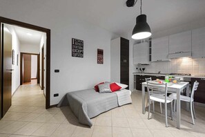 A compact living space with a kitchenette, a dining area, and a small bed.