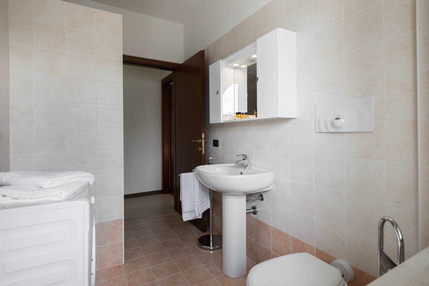 Une salle de bain avec un lavabo blanc, un miroir et un porte-serviettes.