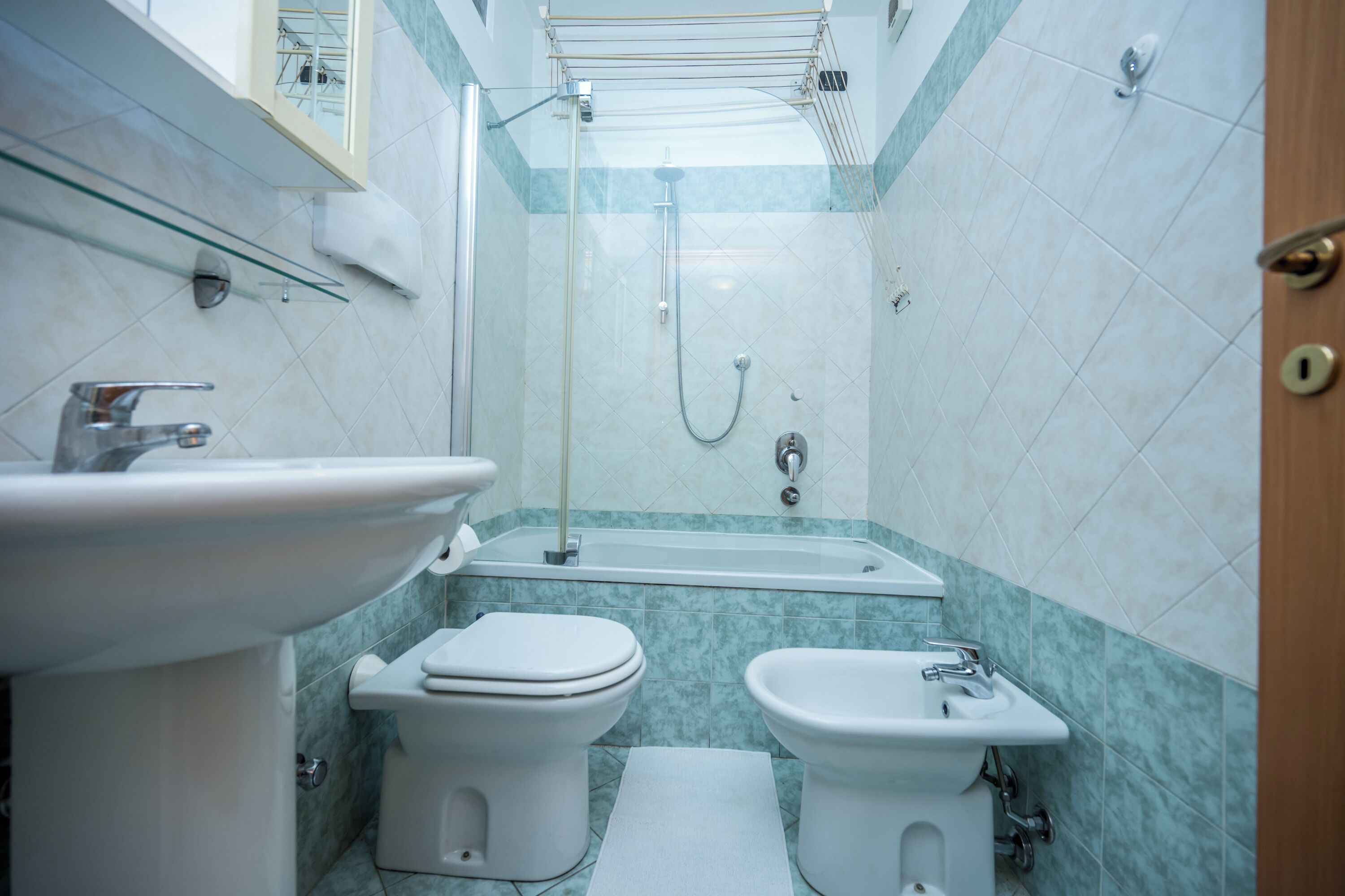 A bathroom with a sink, toilet, bidet, and bathtub.