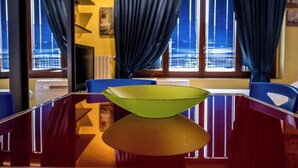 A dining area with a glass table, blue chairs, and a green bowl. - Cozy Suite Arena Milano Santa Giulia (MILANO)