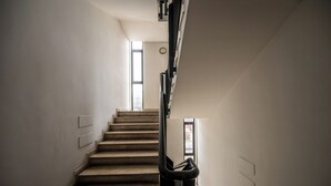 A staircase with a handrail, leading to a landing with a door and a window. - Cozy Suite Arena Milano Santa Giulia (MILANO)