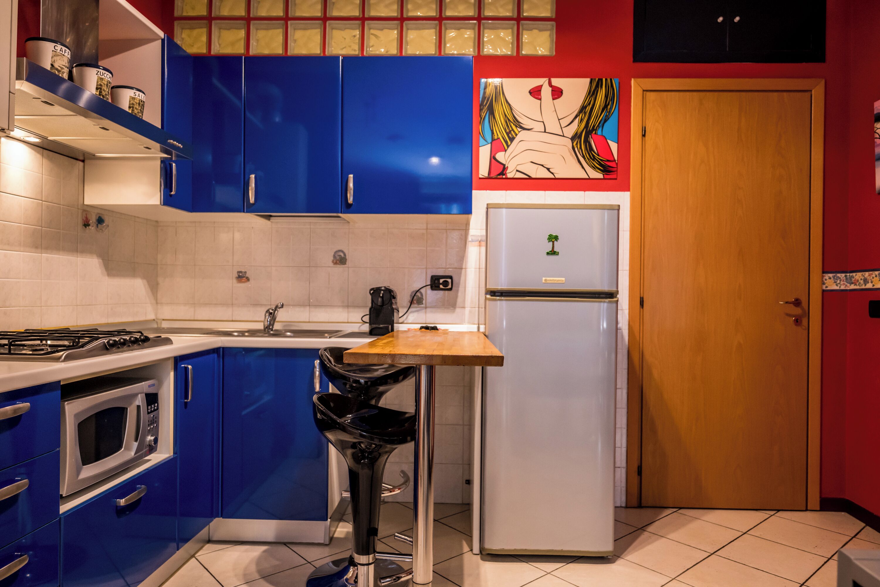 Una cocina con gabinetes azules, un refrigerador blanco y una encimera de madera.