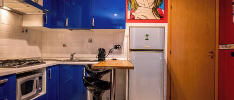 Una cocina con gabinetes azules, un refrigerador blanco y una encimera de madera.