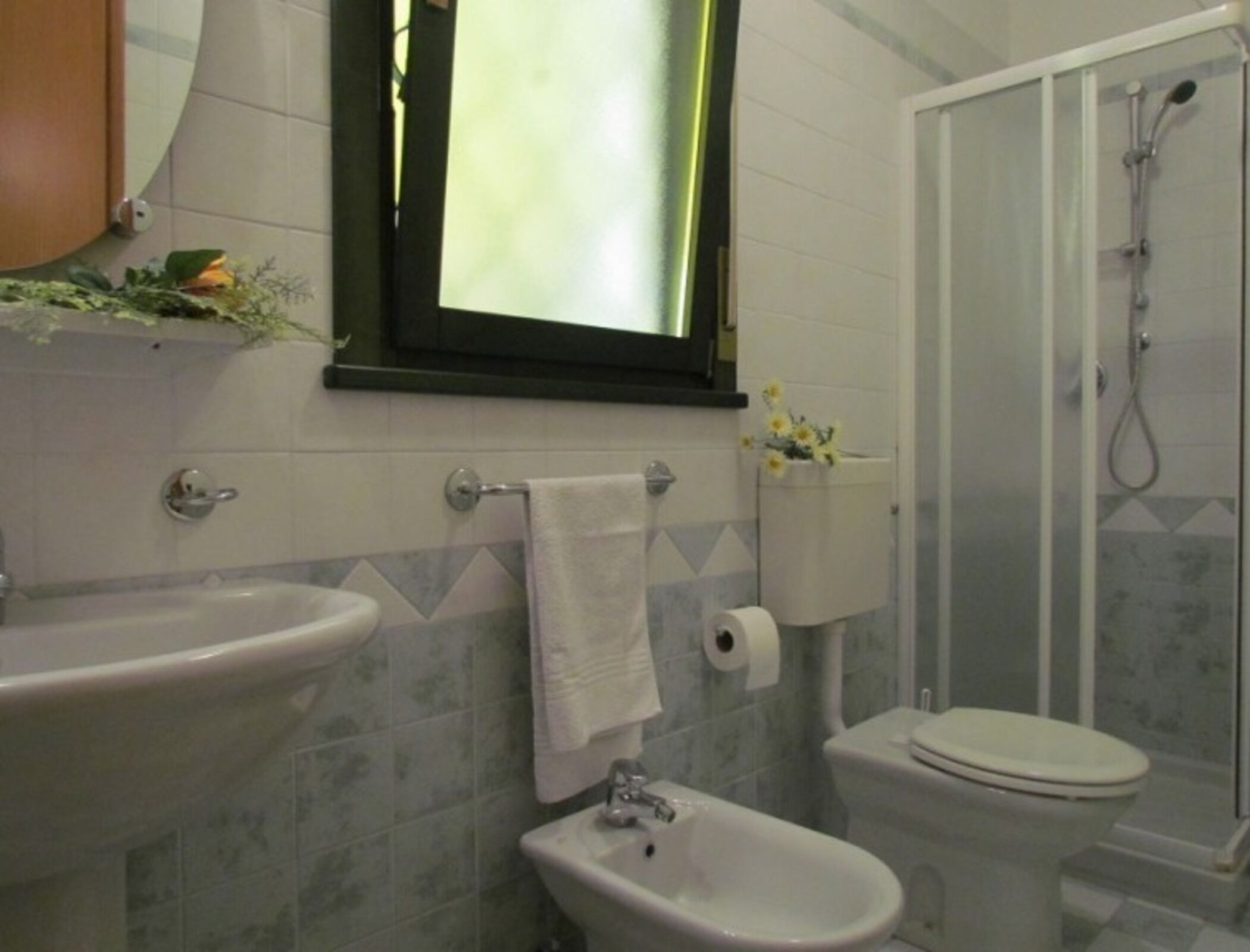 A bathroom with a sink, bidet, toilet, and shower.