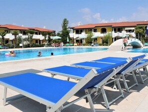 A swimming pool with lounge chairs and a building in the background.