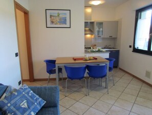 A compact living space with a dining area, kitchenette, and a sofa with patterned cushions.