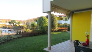 Un patio con piso de baldosas, una mesa con sillas y una pared amarilla.