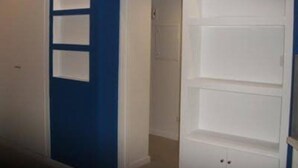 A hallway with a blue wall and white doors. There are three white panels on the wall.