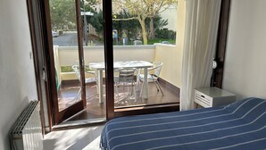 A room with a bed, a small desk, and a balcony with a table and chairs.