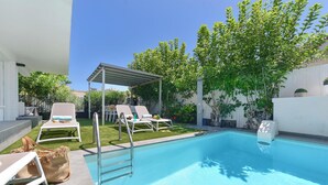 A swimming pool with lounge chairs and a pergola.