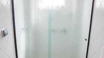 Un baño con cabina de ducha de vidrio, inodoro y perchero para toallas.