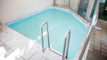 A rectangular indoor swimming pool with metal railings and a tiled floor.